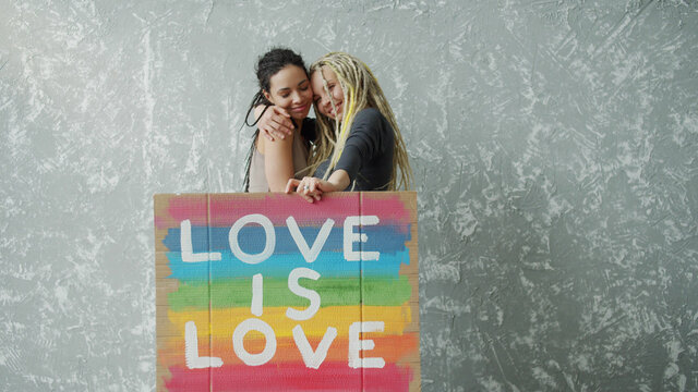 Female lesbian couple holding colorful LGBT poster