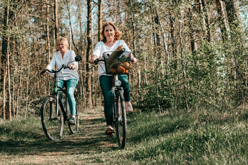 Fototapeta na wymiar Two female Mathure friends are riding bicycle bicycles through the forest. Active lifestyle, hobby
