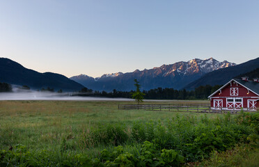 Fototapeta na wymiar Red Barn with morning mist in Pemberton, British Columbia