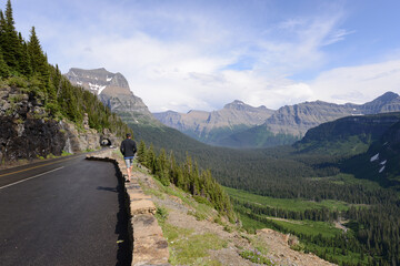 Fototapeta na wymiar Man walking along the side of the Going to the Sun Road in Glacier National Park in Montana