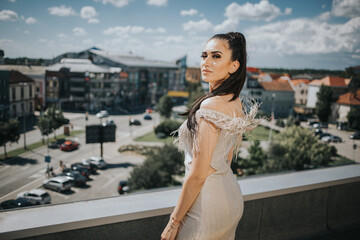 Brunette female posing on a roof in a gorgeous beige evening dress