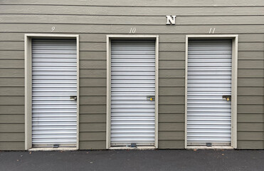 White garage doors with numbers on buildings with tan siding