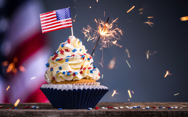 Cupcake and American Flag. Sparklers or fireworks lights burning in a cake. 4th of July, Independence, Presidents Day. Tasty cupcakes with white cream icing and colored stars sprinkles. Sweet dessert. - Powered by Adobe