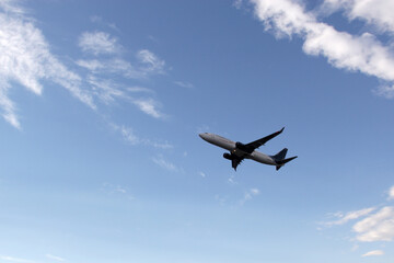 Airplane taking off or landing on runway with blue sky between clouds and mountains
