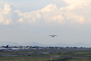 Airplane taking off or landing on runway with blue sky between clouds and mountains
