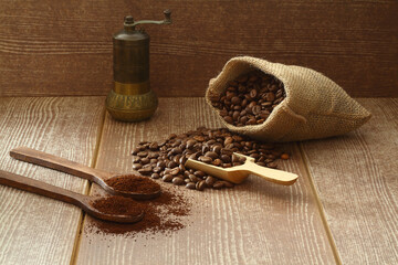 Coffee beans and ground coffee in wooden   spoons on brown background. With old burlap bag and coffee grinder. 