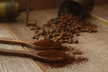 Coffee beans and ground coffee in wooden   spoons on brown background. With coffee pot and coffee grinder. 