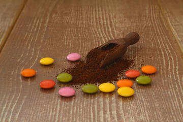 Fototapeta na wymiar multi-colored candy and roasted coffee beans on brown background. With wooden spoon. delicious and exquisite dessert, close up