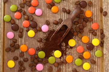 multi-colored candy and  roasted coffee beans  on brown background. With wooden spoon. delicious and exquisite dessert, close up