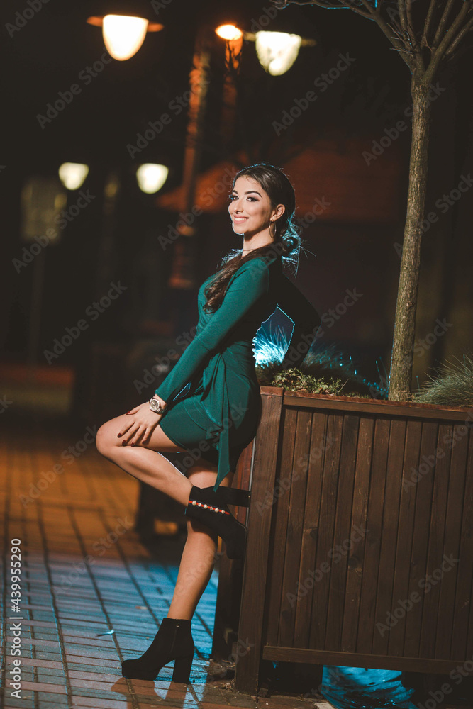 Sticker Vertical shot of a young elegant female in a green dress posing outdoors