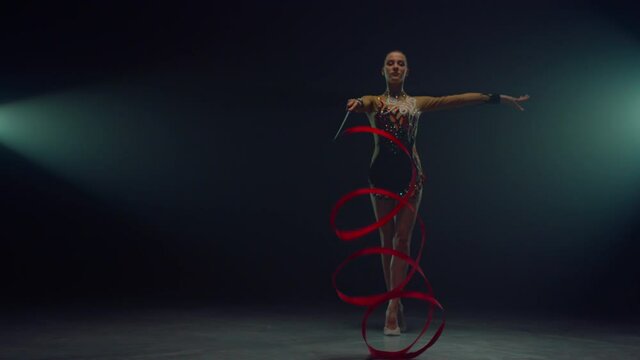 Sports woman twirling gymnastic ribbon. Flexible girl doing rhythmic gymnastics.