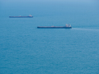 Two empty tankers in the blue sea. Shipping transport goes to the port for loading. Photo side view from the shore.