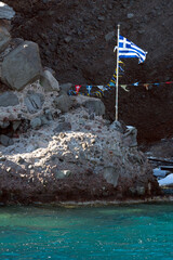 Greek church and flag in a rocky cave in Santorini, Aegean Sea, Greece