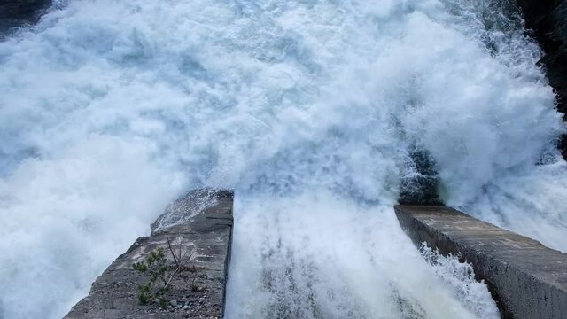 Old dam with flowing water on river. Hydroelectric power station, hydro energy.
