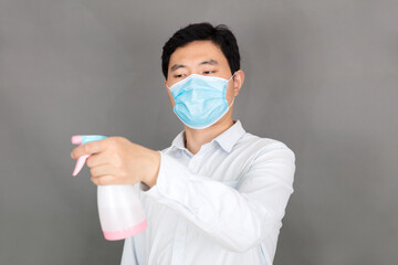 Man wearing a mask and spraying disinfectant in hand