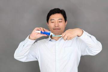 Oriental man squeezes toothpaste on the toothbrush