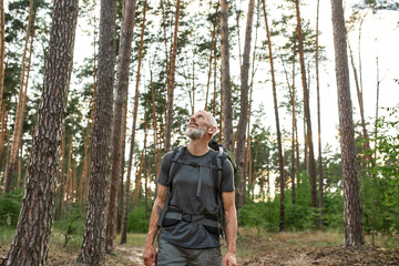 Smiling mature caucasian man trekking alone in forest