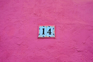 Decorative number 14, tiles on pink painted wall.