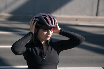 A porter of a female cyclist, illuminated by the morning sun, poses after a workout. Sports in the city. Morning cycling workout. Sport equipment. Sports portrait.