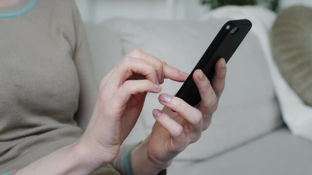 Young woman customer holding phone in hands shopping in app checking social media, enjoy online chat, internet purchase, browse web, download cool freeware application mobile technology, close-up