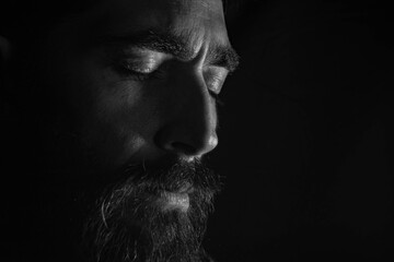 rostro de hombre con sus ojos cerrados en un primer plano y un fondo negro 