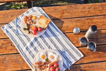 Breakfast in nature. Fried eggs with bacon, fried toast and hot coffee from a thermos