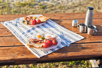 Breakfast in nature. Fried eggs with bacon, fried toast and hot coffee from a thermos
