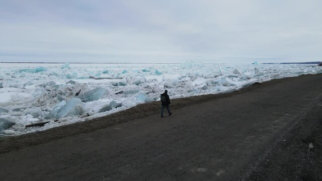 A man walks along the bank along the Yenisei River after an ice drift. Polar night