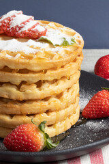 Waffles with fresh strawberries served with honey and sugar.