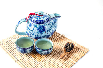 Porcelain teapot and two cups with Chinese tea on the wooden tray, isolated on white.