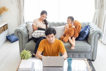Asian Parents and a kid child look at a laptop at home. Family concept.