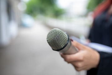 Journalist at news conference, writing notes, holding microphones