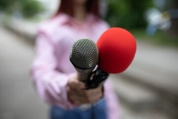 Professional journalist in action, holding microphones and recording notes