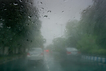Image shot through raindrops falling on wet glass, abstract blurs of traffic - monsoon stock image of Kolkata (formerly Calcutta) city ,
