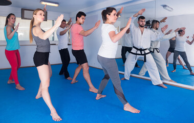 positive european adults attempting to master new moves during karate class.