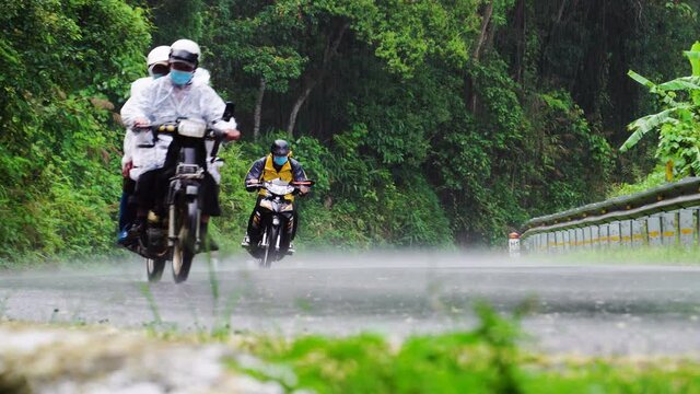 Low-angle shot of bikes travelling up a dangerous and narrow mountain pass in rain, Phan Rang, DaLat road. Riding bikes in the mountains with lush green view of the forest during rainy season.