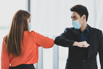Young Asian businessman wearing protective hygiene mask and do elbow contact greeting with woman...