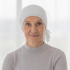 Middle-aged woman cancer patient lost hair from chemo cure process and use clothe cover her head posing to camera with strength eyes and emotion