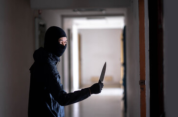 Murder wear the mask holding a knife and Standing in the old apartment, kill and people concept - Criminal or murderer with blood on knife at crime scene.