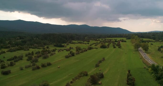 Aerial view of a road, mountains and dark clouds, in rural Slovenia - rising, drone shot