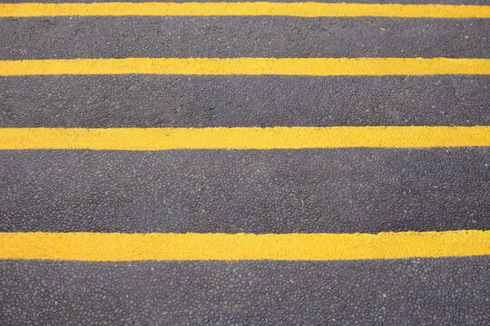 Yellow paint lines on asphalt road surface texture and road stair sign. pedestrian crossing path.