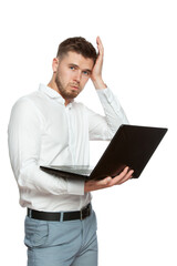 A young asshole with a laptop in his hands has problems with his computer, holds his head and looks into the frame. The figure is isolated on a white background.