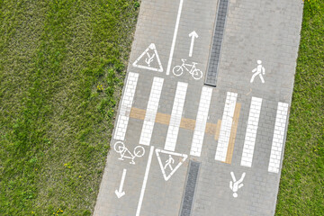 gray bicycle lane. white markings and signs. green grass background. aerial top view.