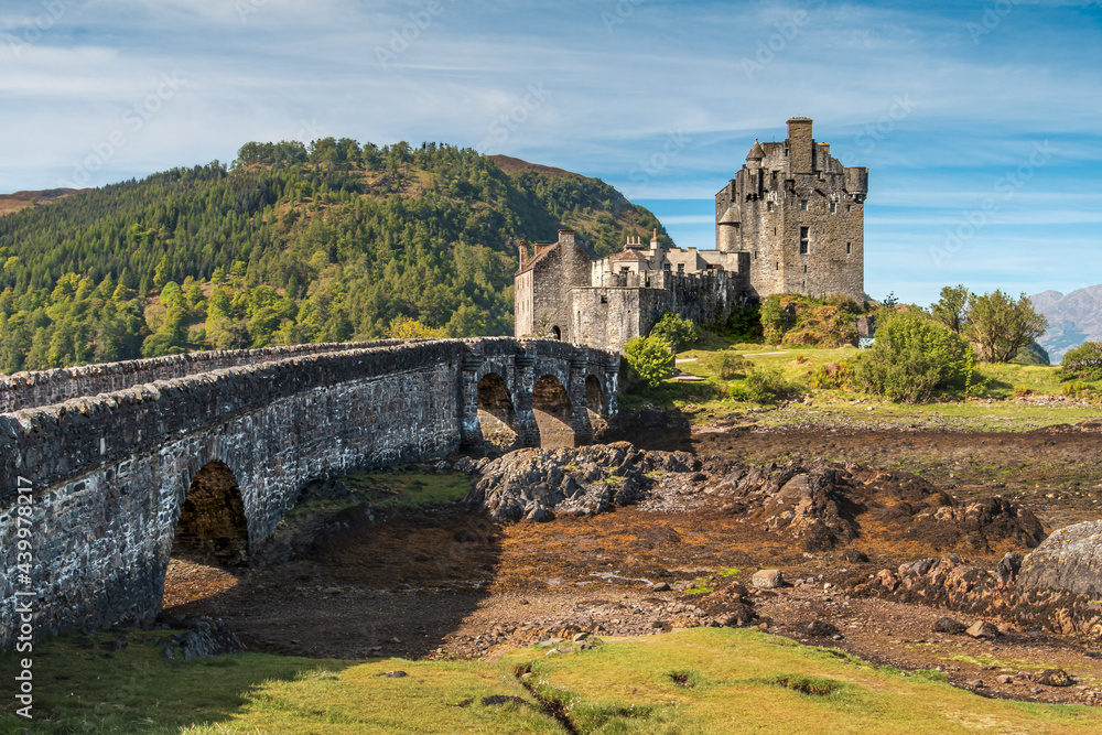 Sticker Breathtaking shot of a wall leading up to the Eilean Donan Castle in Scotland UK at low tide.