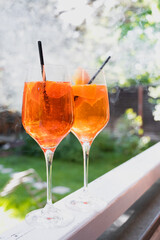 Two glasses with an alcoholic fresh cocktail. Orange mint drink in a glass. Romantic party in nature. 