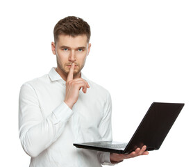 A young man with a laptop in his hands is typing a secret password and showing a gesture of silence, put his finger to his lips. The figure is isolated on a white background.