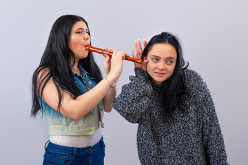two attractive teenager girls having fun with wooden flute isolated on light background © ako-photography