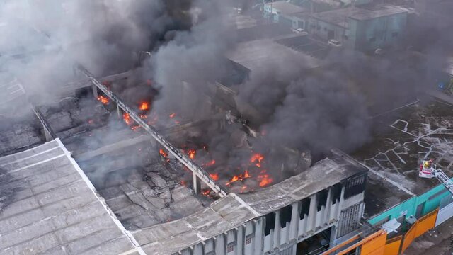 Aerial view around a building fire, smoke rising, aftermath of a bomb explosion - orbit, drone shot