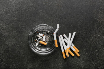 Many cigarettes and ash tray on dark background
