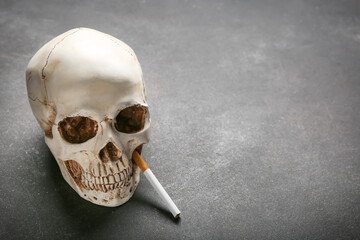 Human skull and cigarette on grey background. Concept of bad habit